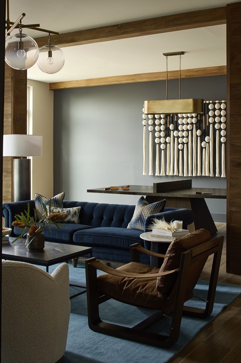 A modern living room with a dark blue sofa and a wooden chandelier.